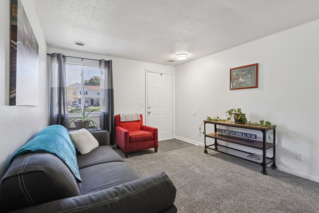 A living room with a grey couch and a red chair.