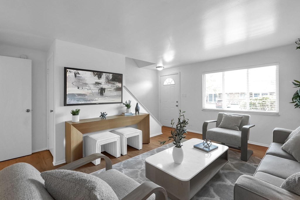 A living room with a grey couch, a white coffee table, and a painting on the wall.
