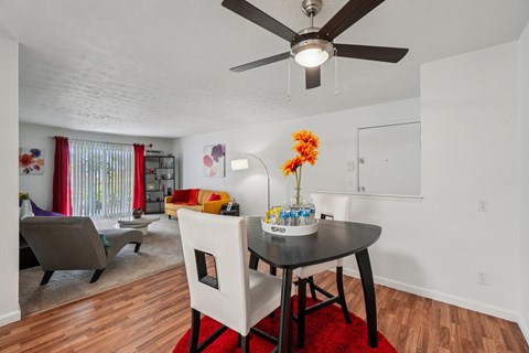 A dining room with a table set for two and a ceiling fan.