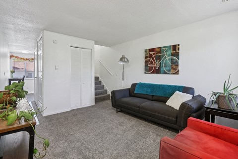 A living room with a black couch and a red chair.
