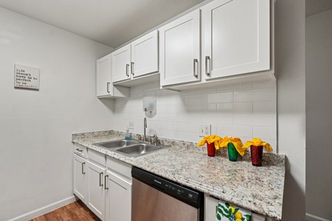 A kitchen with white cabinets and a granite countertop.