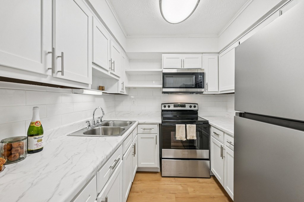 A kitchen with white cabinets and a black refrigerator.