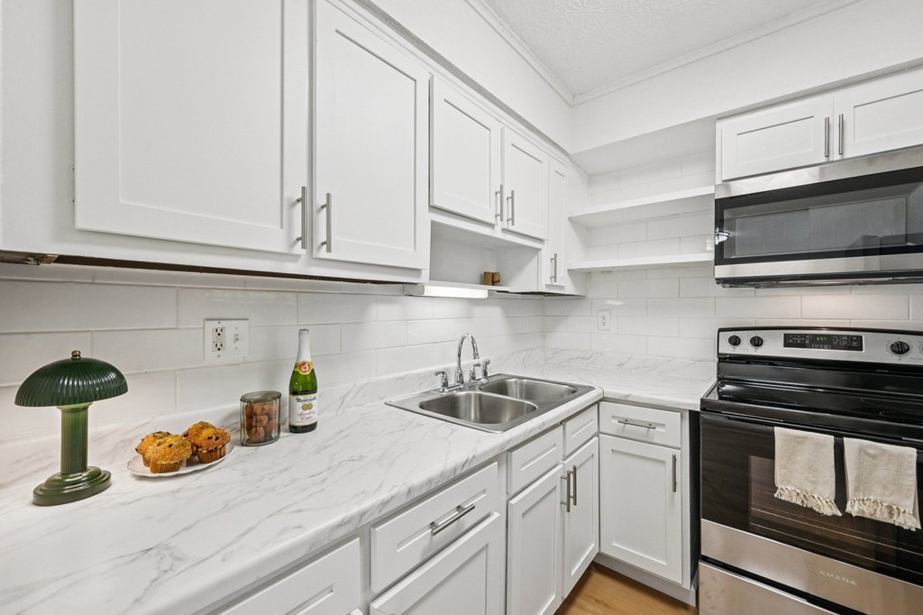 A kitchen with white cabinets and a marble countertop.