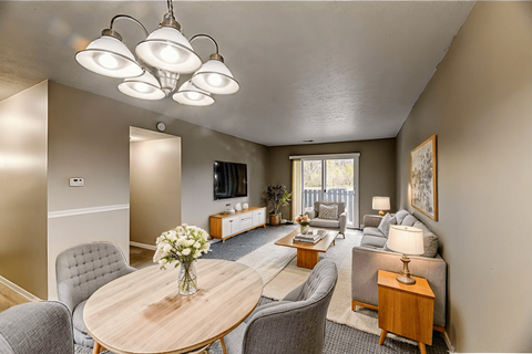 A well-lit living room with a dining table and grey chairs.