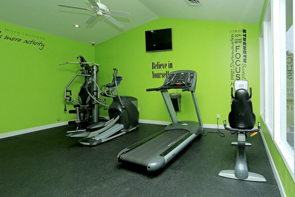a gym with various machines and a tv on the wall