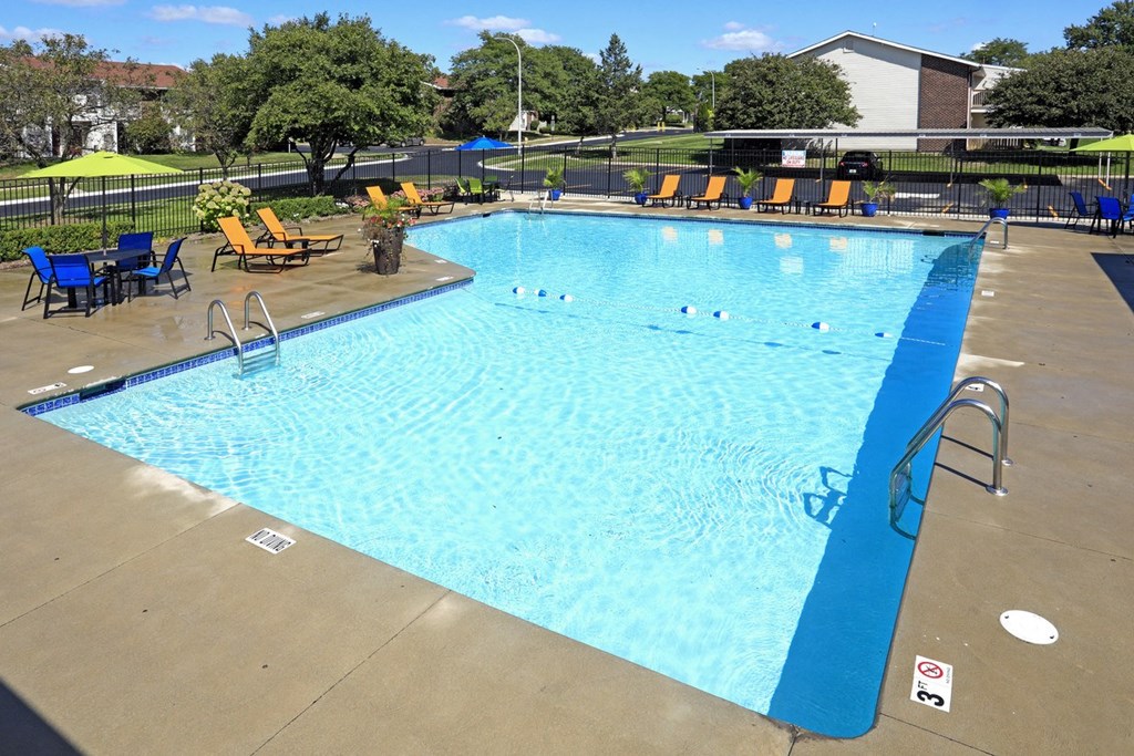a swimming pool with chairs and umbrellas around it