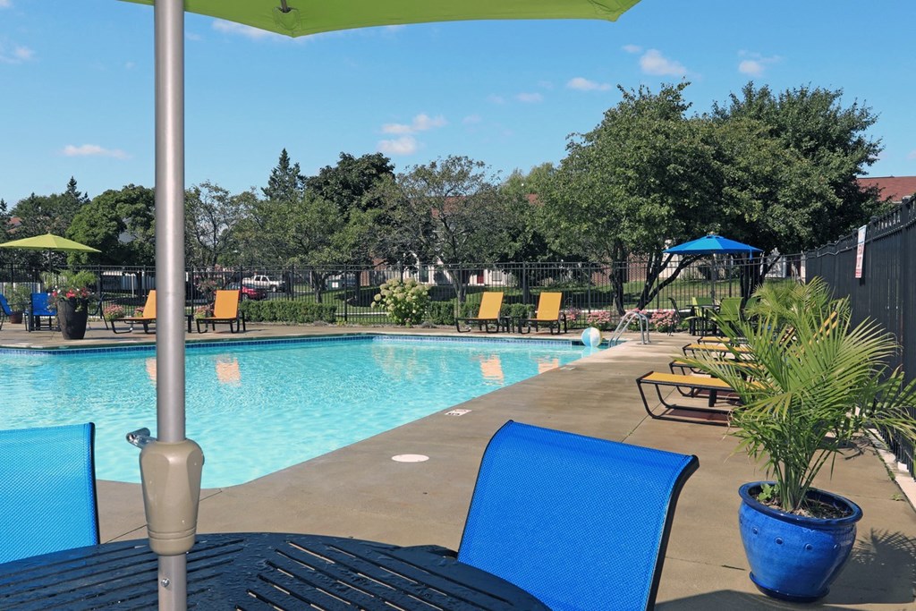 a swimming pool with blue chairs and umbrellas and a poolside umbrella