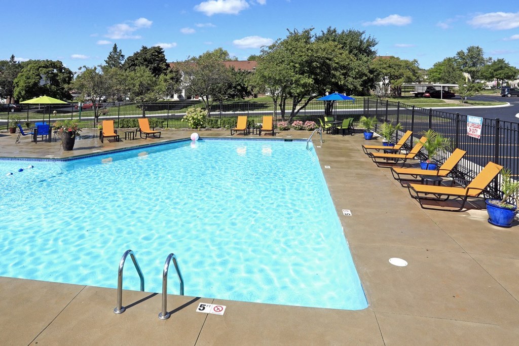 a swimming pool with yellow chairs and a fence around it