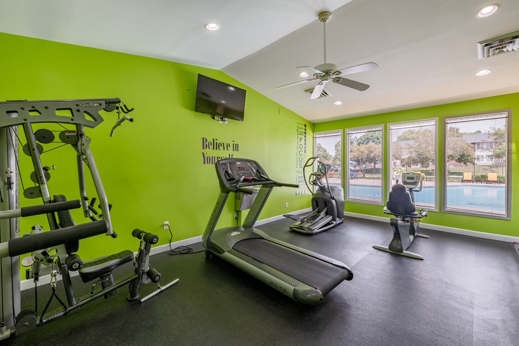a gym with treadmills and other exercise equipment and a tv