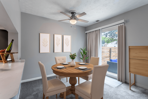 A dining room with a table set for two and a ceiling fan.