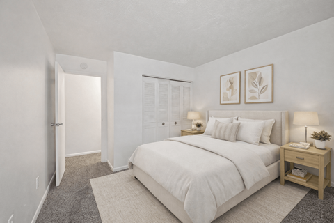 A bedroom with a large bed, a nightstand, and a small table with a plant on it.