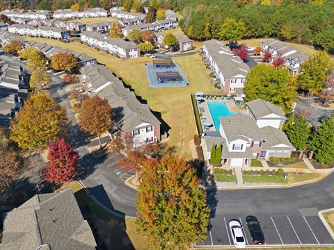 A bird's eye view of a residential area with houses, trees, and a swimming pool.