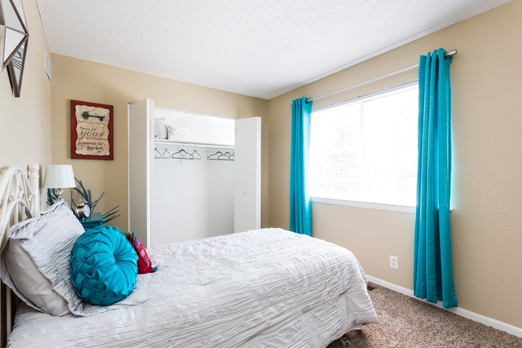 A bedroom with a white bed and a blue pillow.