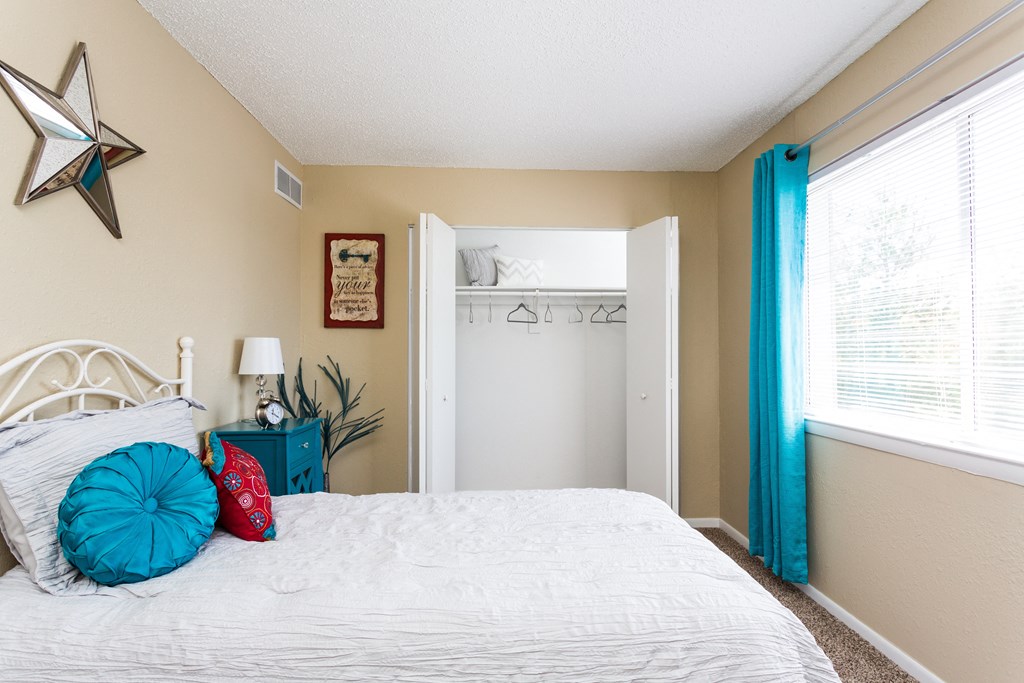 A bedroom with a white bed and a blue pillow.