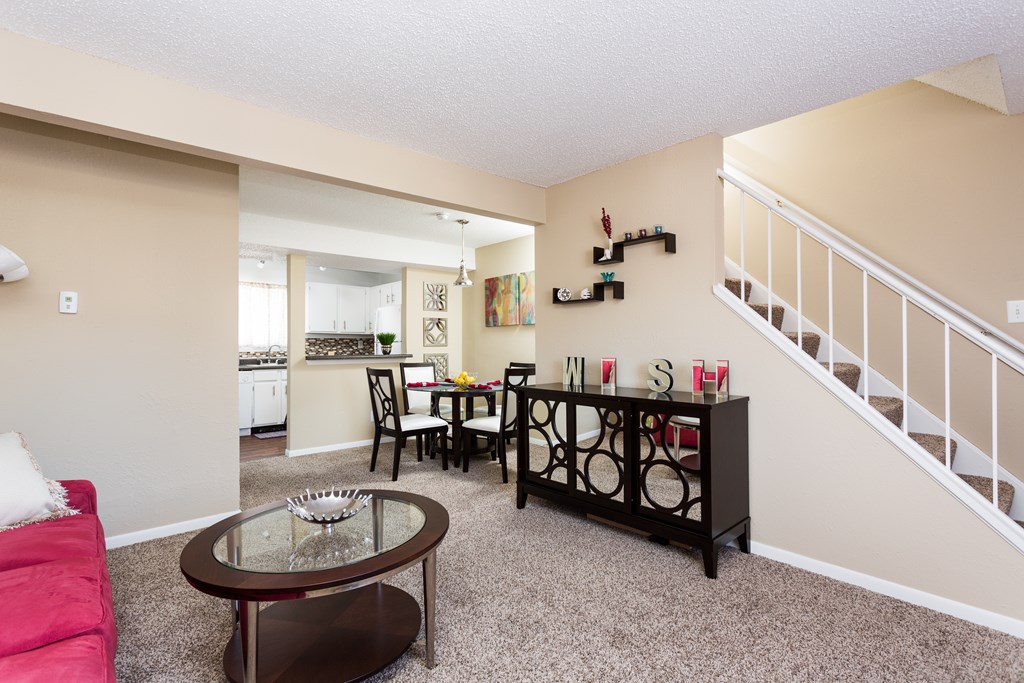 A living room with a red couch, a glass coffee table, and a staircase.