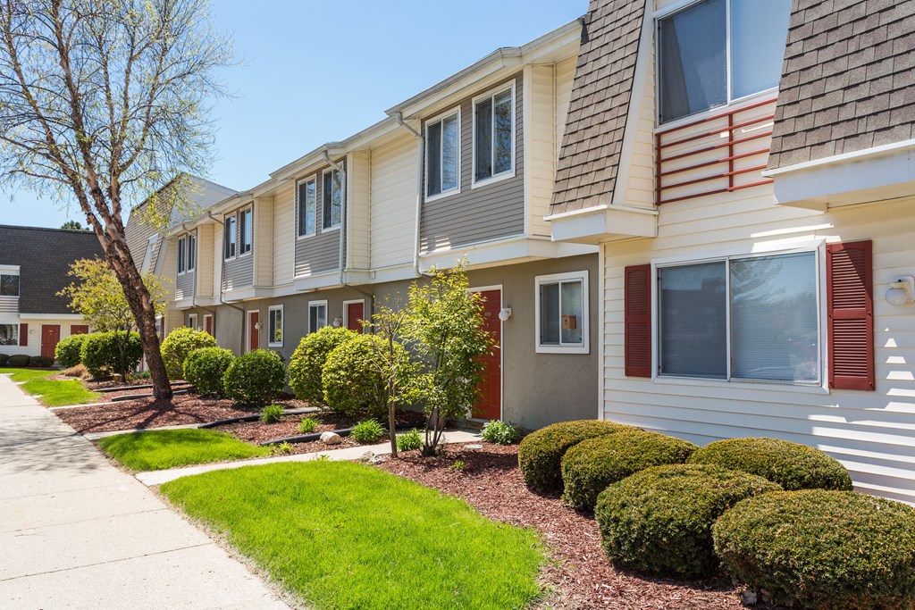 A row of houses with green lawns and trees.