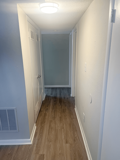 a hallway with wood flooring and a door to a bedroom