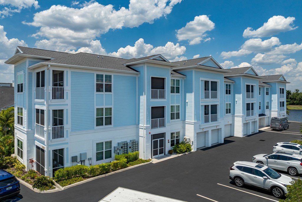 a row of blue apartment buildings with cars parked in front of them