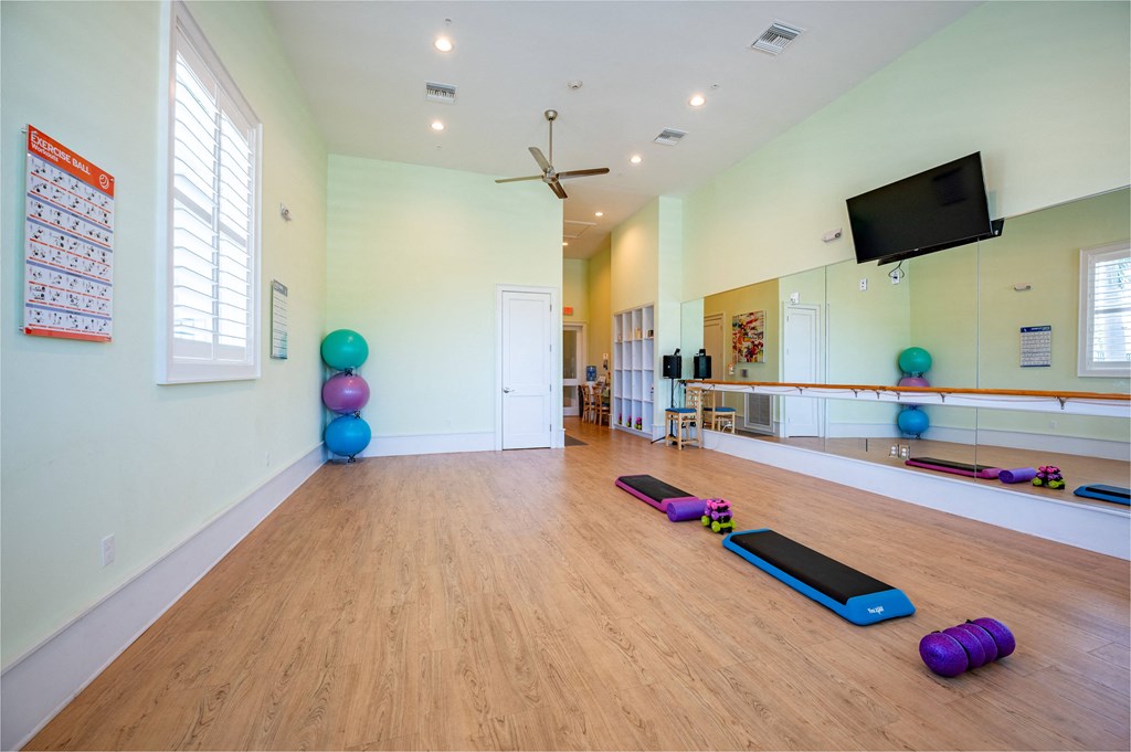 a yoga room with yoga mats on the floor and a tv on the wall