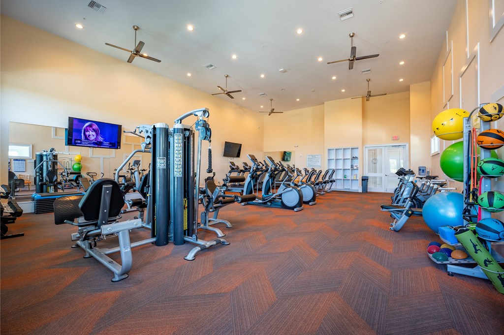 a gym with cardio equipment and weights on a wooden floor