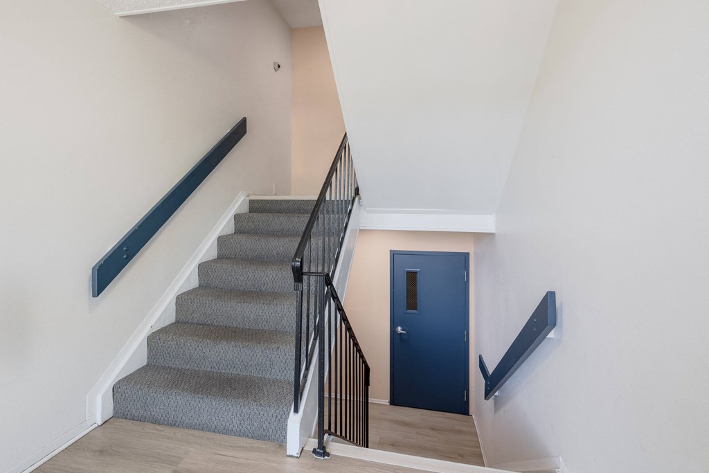 a staircase with a blue door at the bottom of the stairs