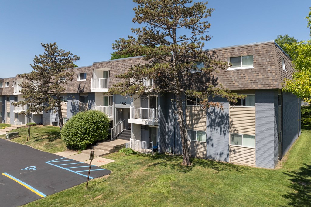 an exterior view of a grey apartment building with balconies and trees