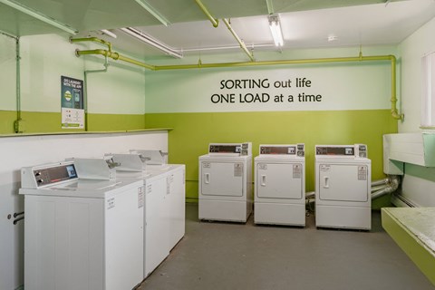 a laundry room with four washing machines and a sign on the wall