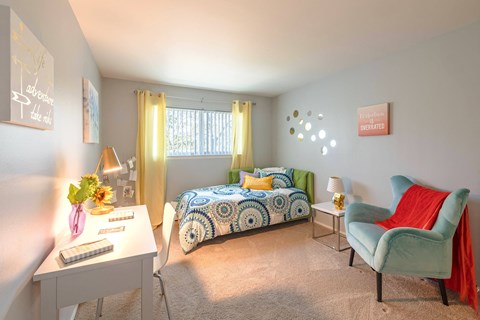 A bedroom with a bed, a chair, and a desk.