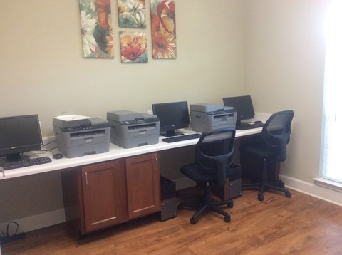 A room with a desk, chairs and computers.