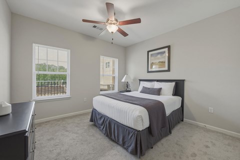 A bedroom with a bed, a ceiling fan, and a window with blinds.