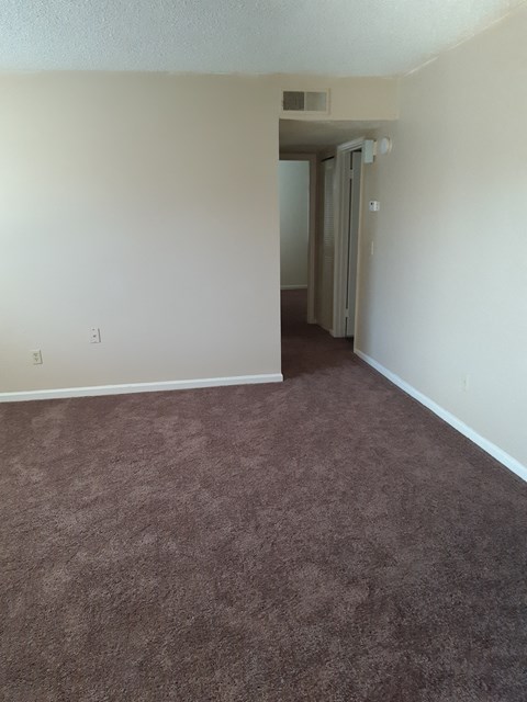 an empty living room with carpet and white walls