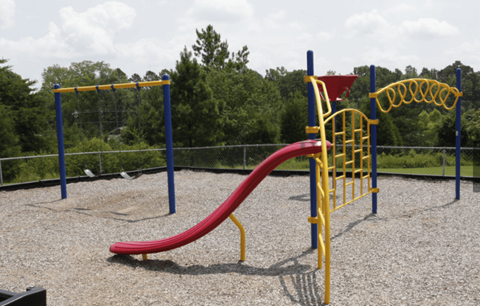 a playground with a red slide and a blue and yellow swing set