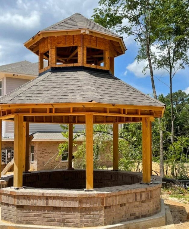 a large wooden gazebo with a brick patio