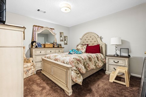 A bedroom with a large bed and a vanity table.