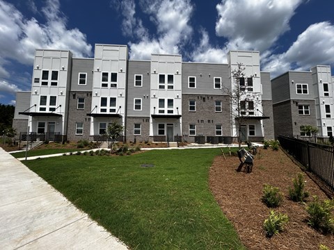 A modern apartment complex with a well-maintained lawn and landscaping.
