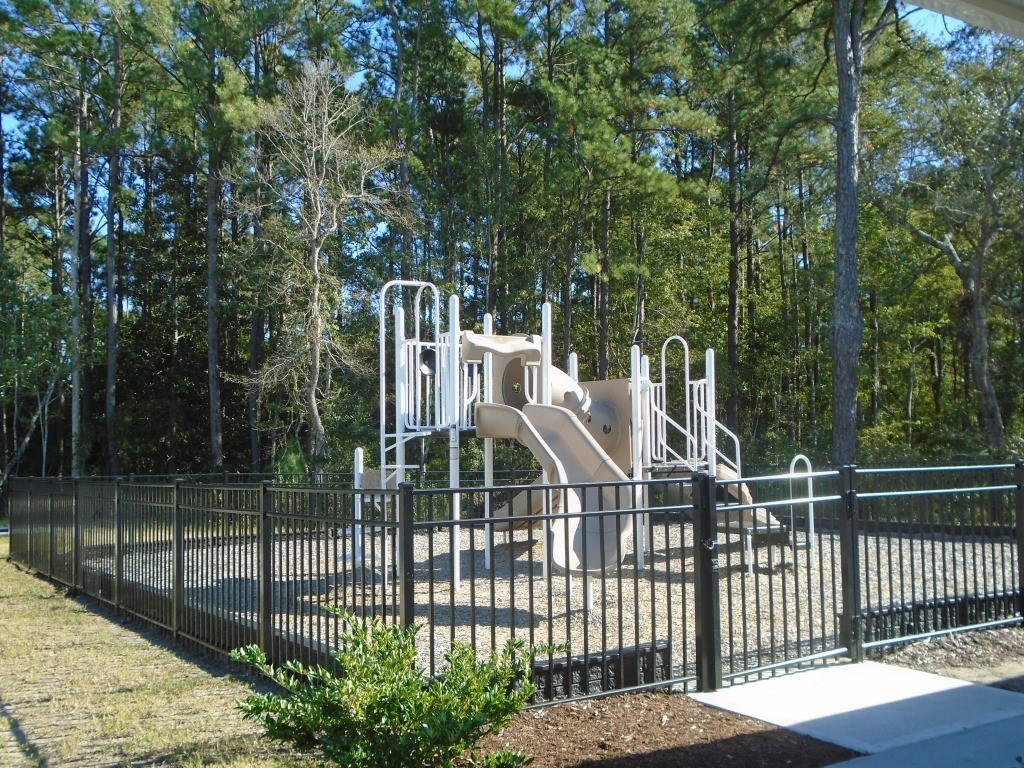 a playground with slides in a park behind a fence