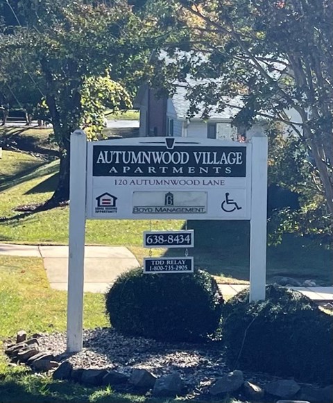 a sign for theatomworld village apartments in a park