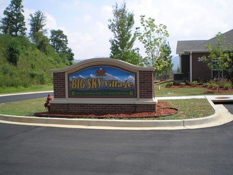 a sign for big sky village in front of a road
