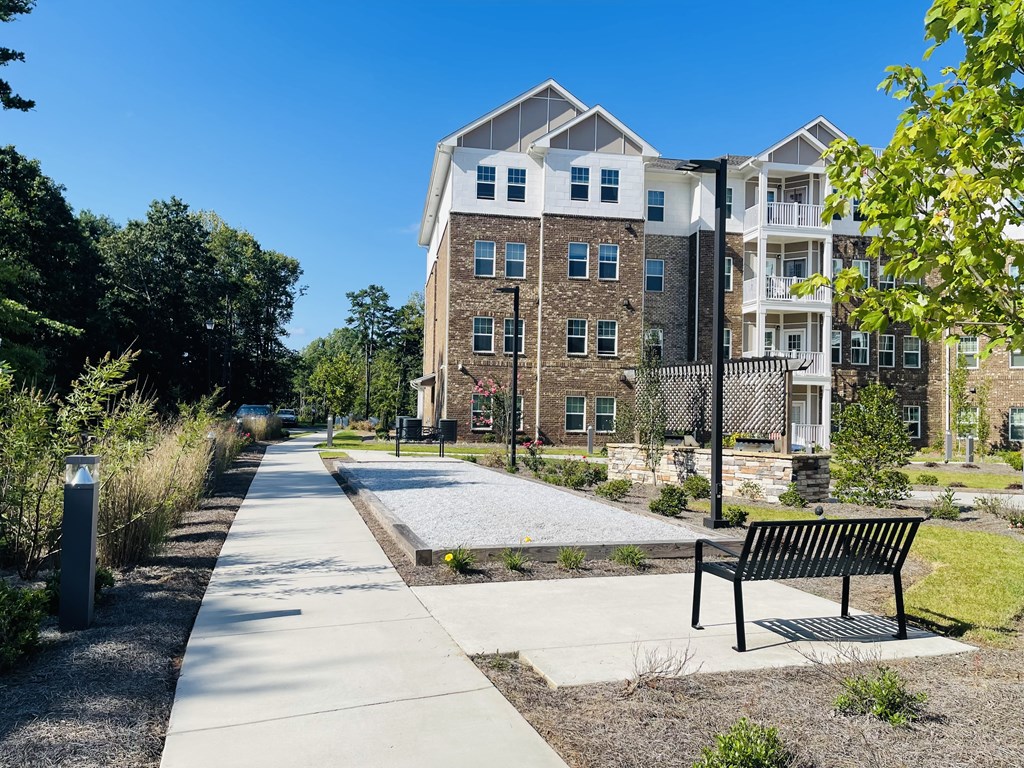 A black bench sits on a concrete slab in front of a building.
