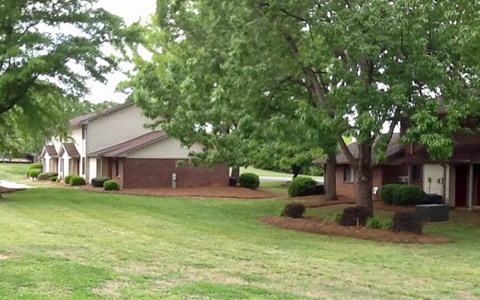 a house with a yard and trees in front of it
