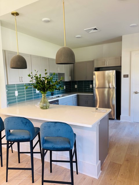 A kitchen with a white counter and blue chairs.