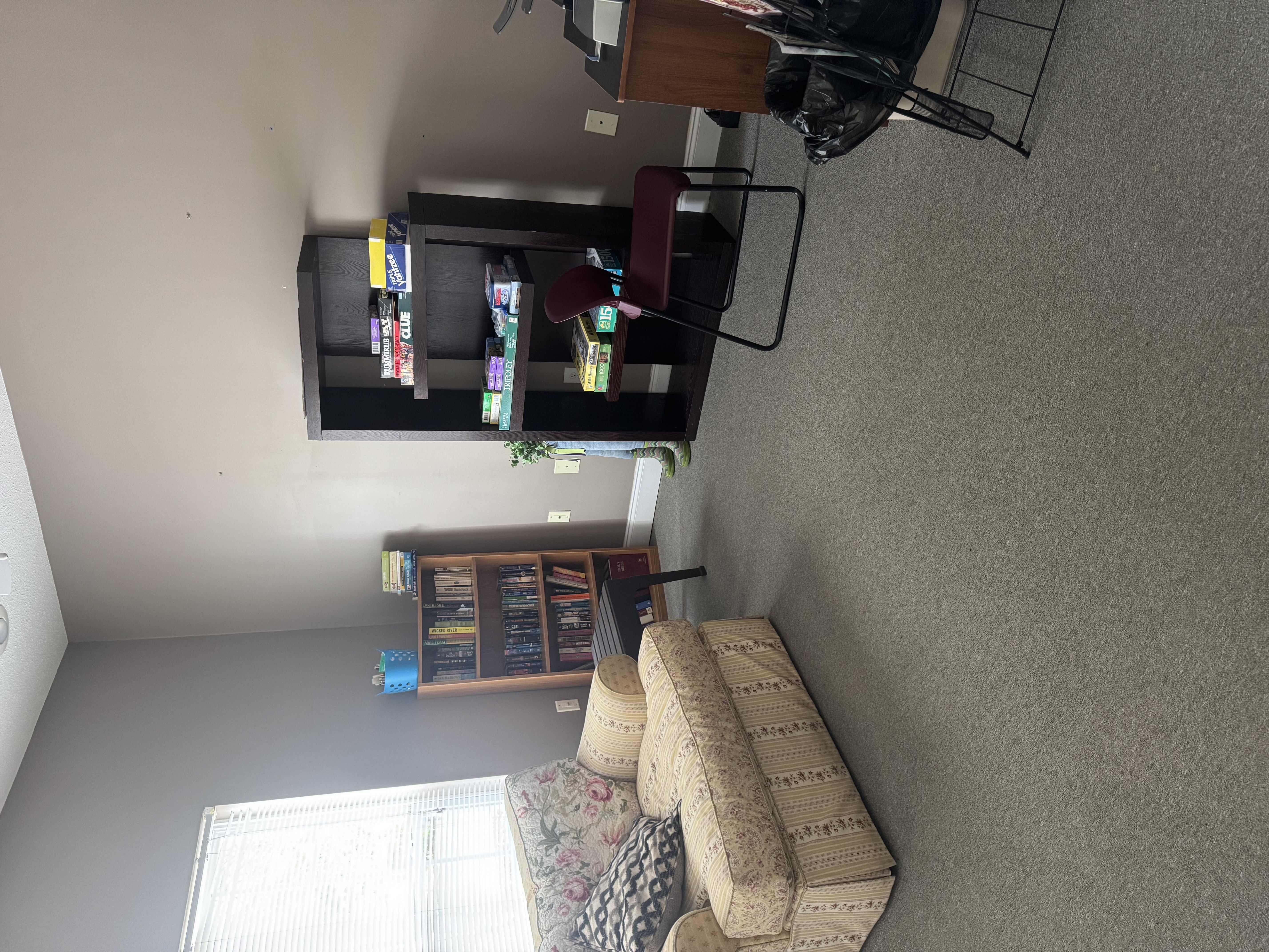 A living room with a couch, a television, and a window with blinds.