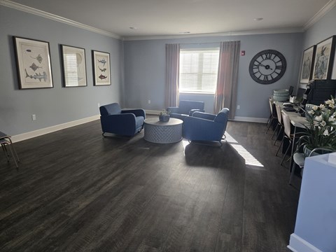 A living room with a grey wall and a large clock on the wall.