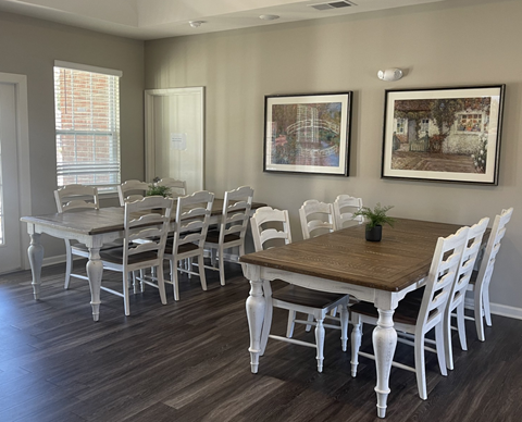 A dining room with a wooden table and white chairs.