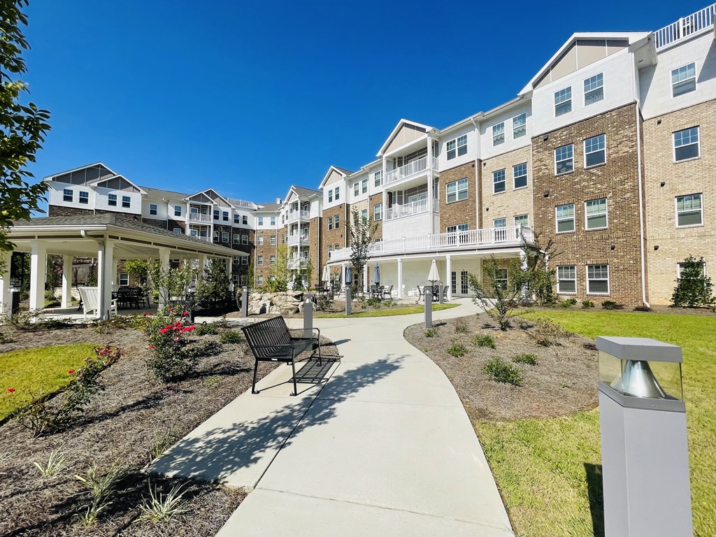 A sunny day at a residential complex with a walkway and a bench.