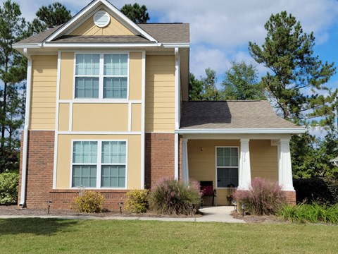 a yellow house with a lawn in front of it