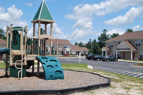A playground with a green slide and a wooden tower.