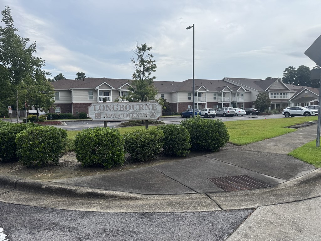 A street view of a residential area with a sign that reads "LONGBOURNE APARTMENTS".