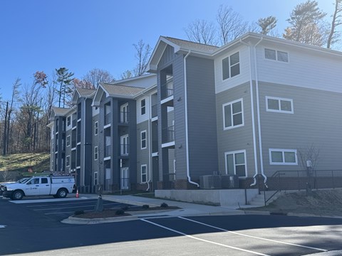 A white truck is parked in front of a two-story apartment building.
