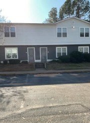 A two-story house with a grey front door and a small porch.